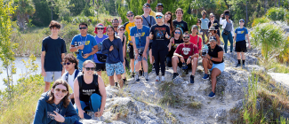 Large group of students standing on a rock posing for a picture in hiking attire